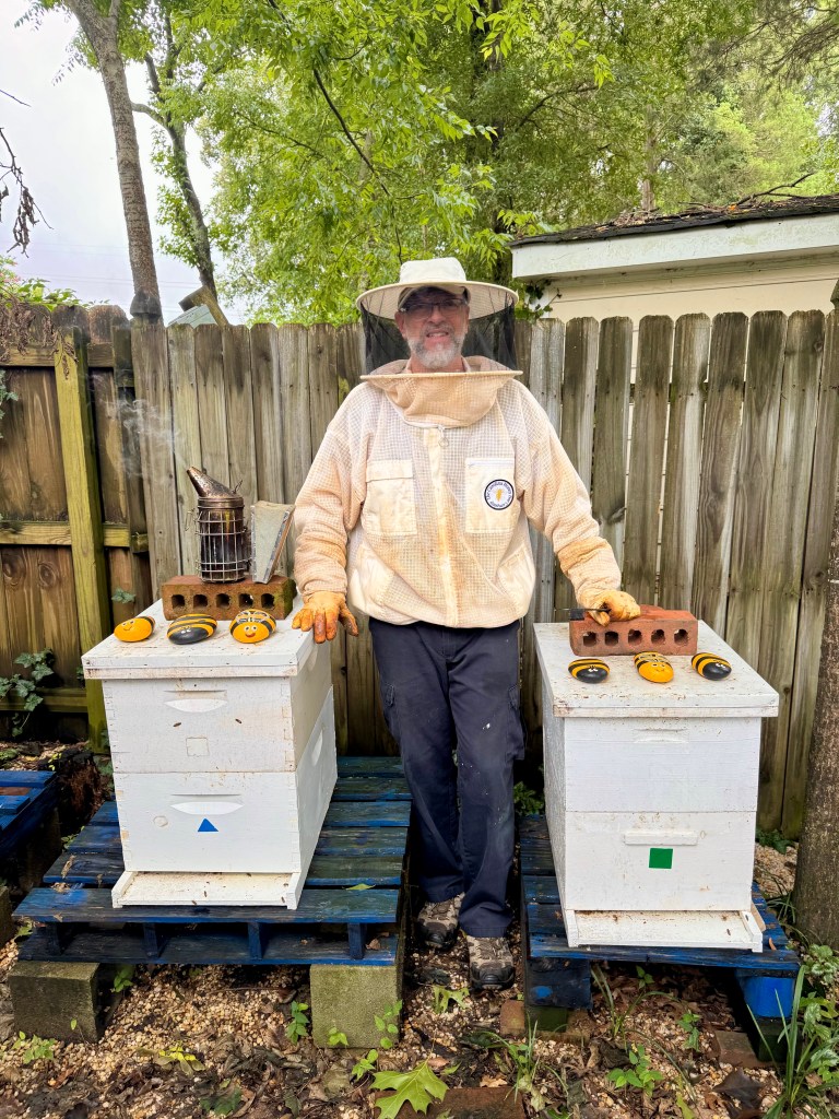 Hal Hoffmann in his beekeeping gear, standing between two hives at the Halo Honey apiary