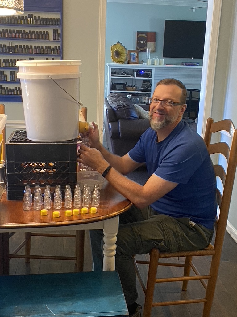 Hal Hoffmann bottling honey by hand into small glass jars lined up on the table