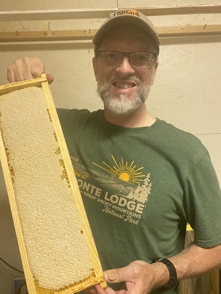 Hal Hoffmann holds up a frame of fully capped honeycomb, ready for extracting