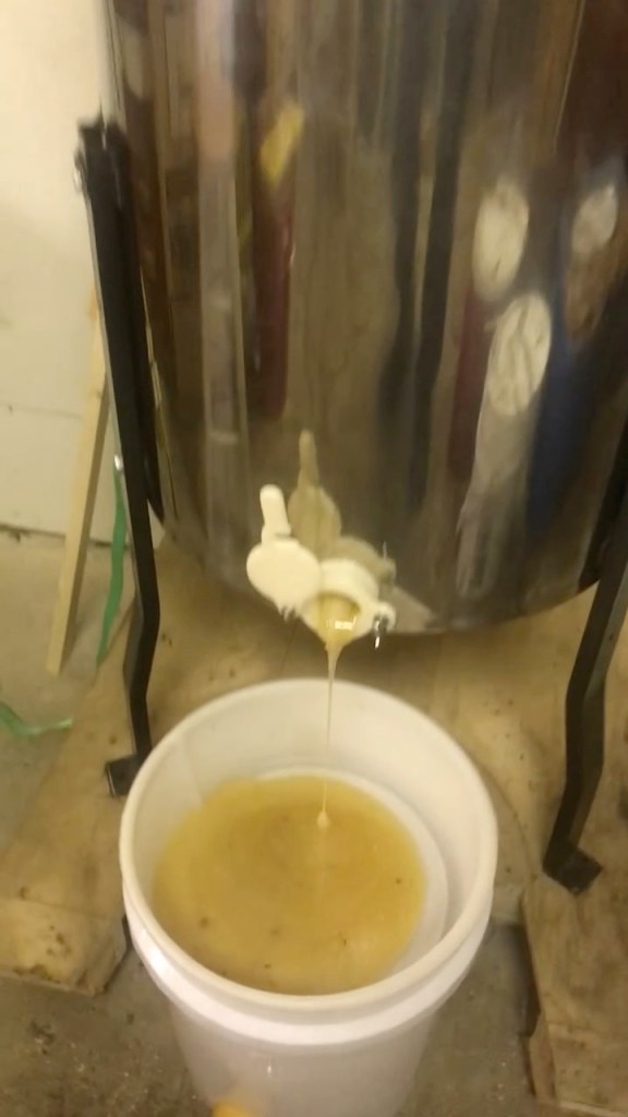 Honey draining from the extractor's honey gate into a collection bucket during extraction